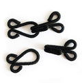 Close-up of large black fur cotton braided hooks and eyes fasteners.
