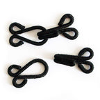 Close-up of large black fur cotton braided hooks and eyes fasteners.