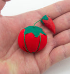 Close-up of the bright tomato pin cushion, ideal for sewing projects.