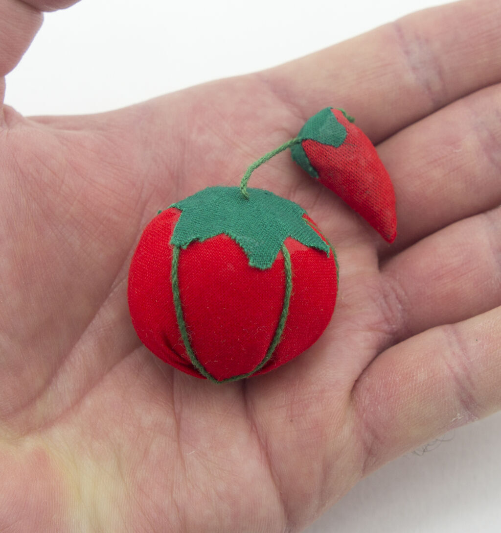 Close-up of the bright tomato pin cushion, ideal for sewing projects.