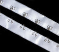 Close-up of silver hook and eyes on white satin ribbon tape.