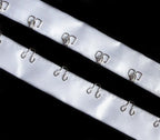 Close-up of silver hook and eyes on white satin ribbon tape.