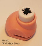 Craft paper punch in use, creating leaf shapes