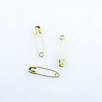 Close-up of gold tone safety pins in a box.