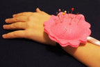 Pink wrist pin cushion worn on a wrist, showcasing its practical use.