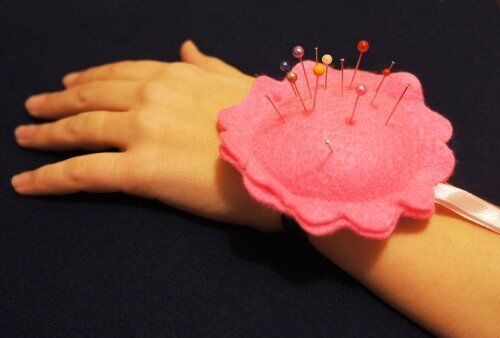 Pink wrist pin cushion worn on a wrist, showcasing its practical use.