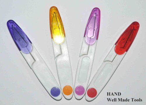 Thread snips being used to cut threads near a sewing machine