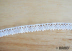 Roll of white cotton lace trim displayed on a craft table.