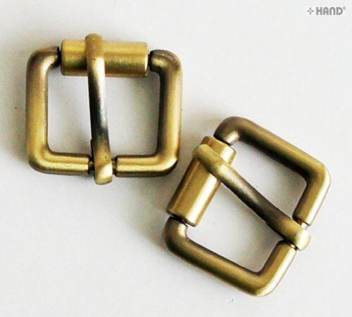 Close-up of a small vintage gold tone metal belt buckle showing detail.