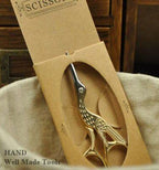 Scissors displayed on a crafting table with embroidery supplies.
