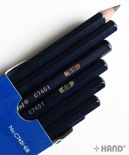 Artist using black charcoal drawing pencils on sketch paper