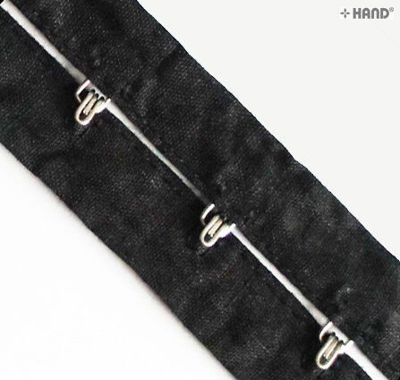 Silver hook and eyes arranged on a black tape background