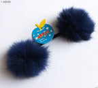 Flat lay of double pom pom hair bands in various colours on a surface