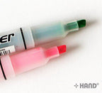 Twin highlighter in use, highlighting text on paper.