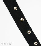 Close-up of silver eyelets on black cotton tape for sewing.