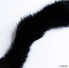 Close-up of black rabbit fur sew in pipe trim on a white background.