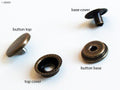 Close-up of 4-part silver press stud buttons on a white background.