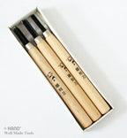 Three professional woodcarving chisels arranged on a wooden surface.