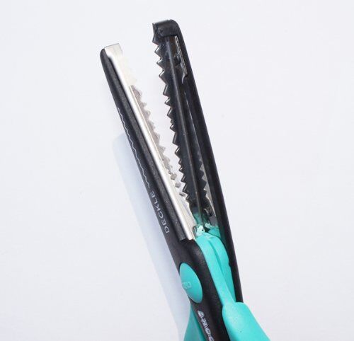 Scissors cutting colourful paper with decorative edges
