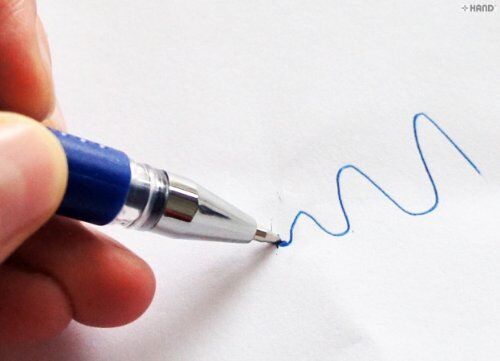 User holding a fine point 0.5mm blue ink pen while writing