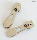 Silver polished zip pull attached to a fabric swatch.