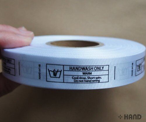 Roll of fabric printed wash care labels showing WASH ONLY instructions.