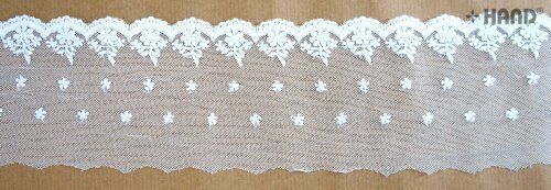 Close-up of white embroidered tulle lace edging on a craft project.
