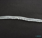 Tiny white pom pom trim displayed with sewing tools and fabric
