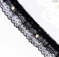 Black decorative lace ruffle trim with pearls on a white background.