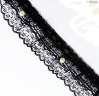 Black decorative lace ruffle trim with pearls on a white background.