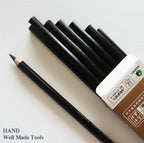 Twelve black charcoal sketching pencils arranged neatly