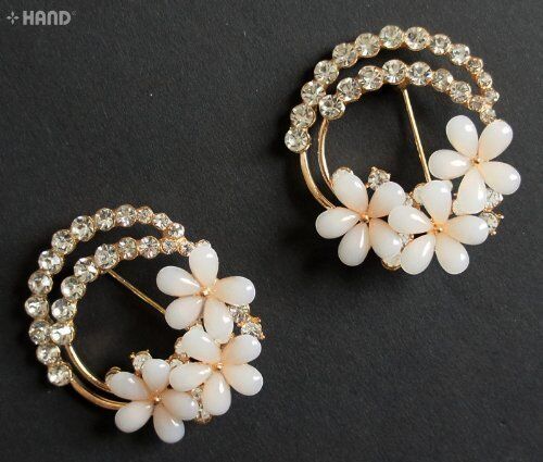 Two elegant crystal cream flower gold brooches displayed together.