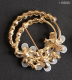 Close-up of a crystal cream flower brooch with gold detailing.