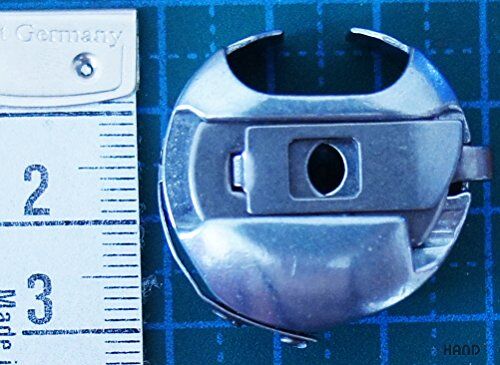 Towa bobbin case placed next to a sewing machine