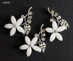 Three clear crystal and silver flower brooches displayed together.