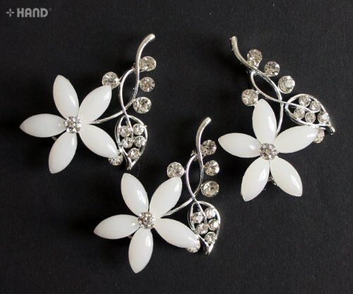 Individual clear crystal and silver flower brooch on a white background.
