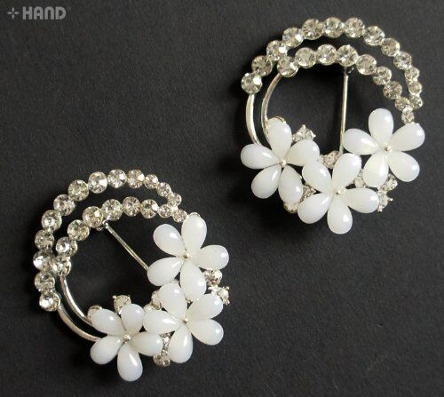Two crystal white flower brooches displayed on a neutral background.