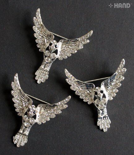 Three elegant clear crystal bird silver brooches displayed together.