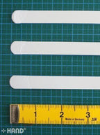 Close-up of a single metal white boning piece, showing its width.