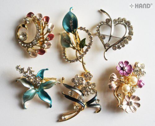 Three assorted brooches with crystal rhinestones displayed together.
