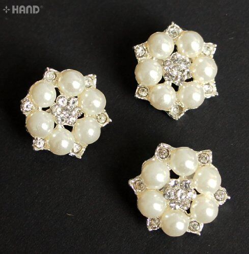 Three small pearl and clear crystal brooches displayed together.