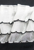 Close-up of decorative three layer frill trim in white and black.