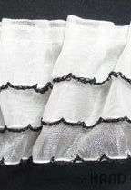 Close-up of decorative three layer frill trim in white and black.