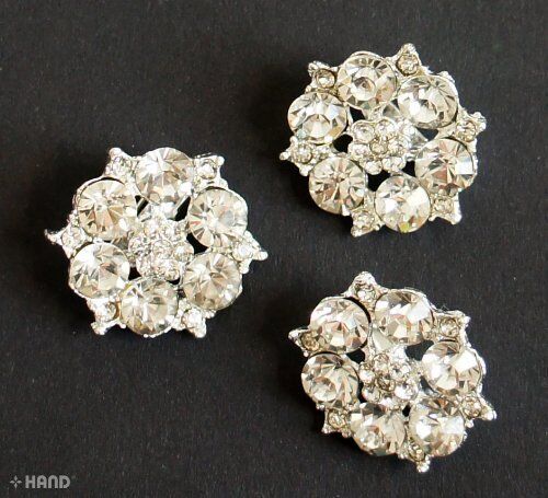 Small silver brooch with clear crystals, elegant design.