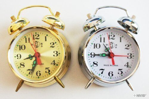 Gold twin bell metal alarm clock on a wooden table