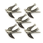 Close-up of a silver colour swallow pendant on a white background.