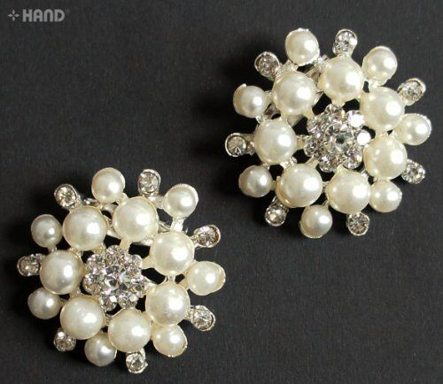 Elegant pearl and clear crystal brooch displayed on a fabric background.
