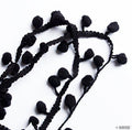 Close-up of mini black pom pom fringe showing texture and detail.