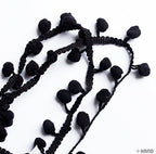 Close-up of mini black pom pom fringe showing texture and detail.