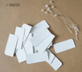 Plain white small paper tags with nylon lock string displayed.